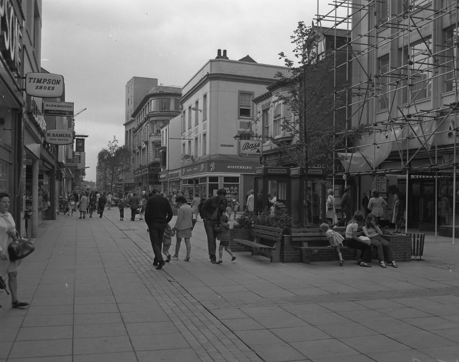 Black and white photograph of a street in Middlesbrough with people and shops.