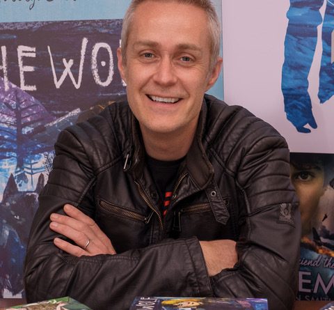Man wearing leather jacket with arms crossed and smiling at the camera
