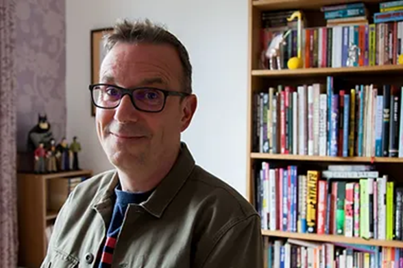 Man with grey hair and glasses smiling at the camera