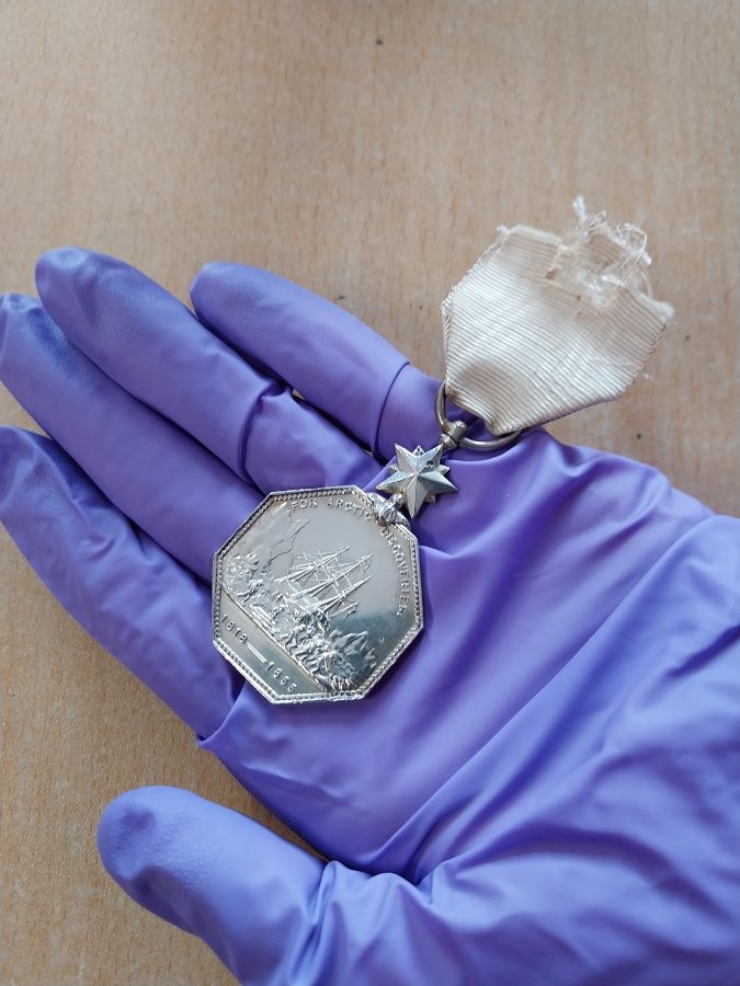 polar medal with a white ribbon in a gloved hand.