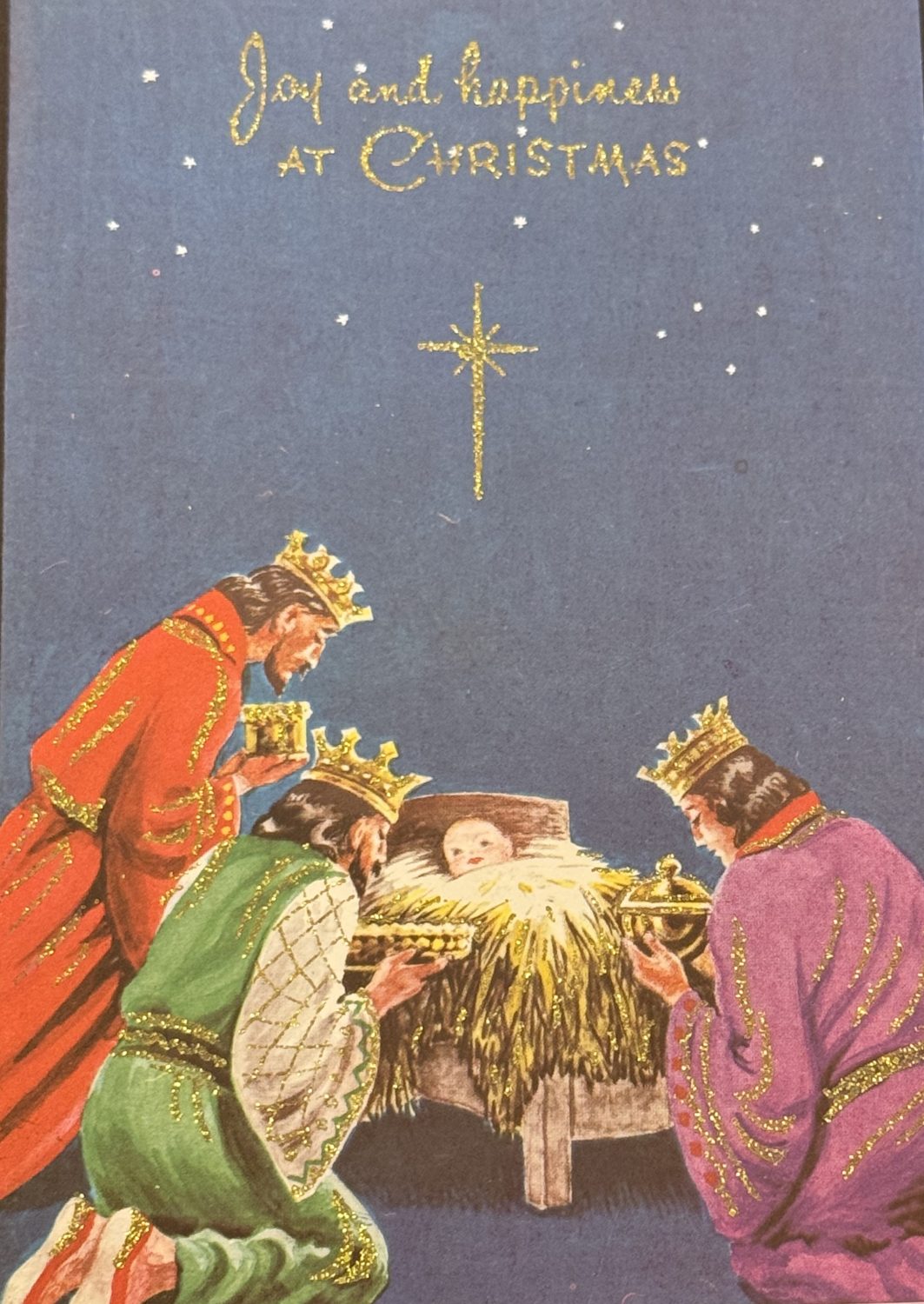 A Christmas card from Museum of Hartlepool’s collection showing the baby Jesus in a manger, surrounded by the three wise men. They are kneeling and presenting gifts to him.