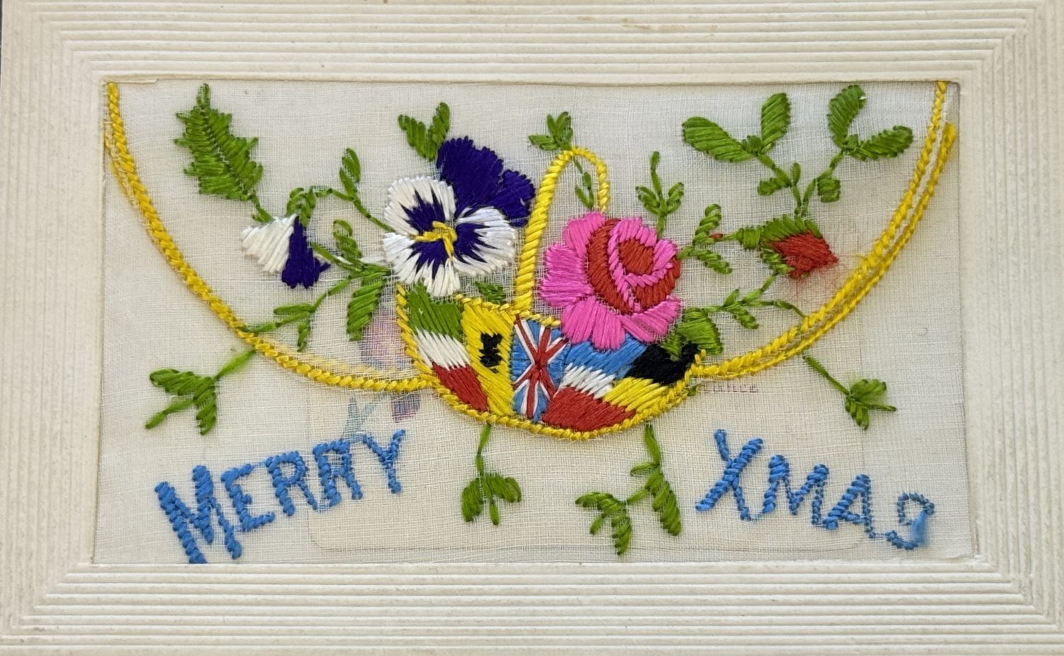 An embroidered xmas card from Museum of Hartlepool's collection. The card has flowers and a basket with various flags. It says 'Merry Xmas'