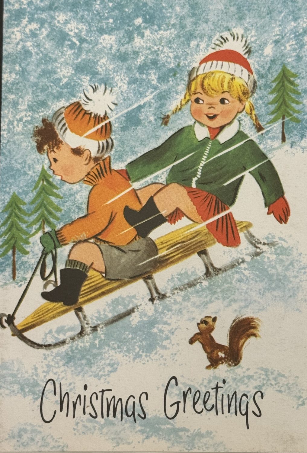 A Christmas card from Museum of Hartlepool’s collection. The card shows two children playing on a sledge in the snow. There's also trees in the background and a squirrel in the foreground.